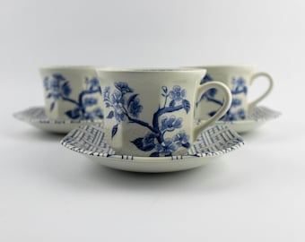 Puede incluir: Tres tazas de té de cerámica color hueso con platos a juego, decoradas con patrones de ramas florales azules. Los platos presentan un borde con diseño geométrico, mientras que las tazas muestran flores azules detalladas.