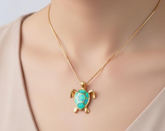 May include: Gold-toned necklace featuring a turtle pendant. The pendant has a turquoise-colored, opal-like center and gold-colored accents. The necklace is worn around the neck.