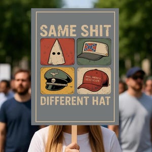 May include: A grey sign held by a person with the words "SAME SHIT DIFFERENT HAT" in large, bold letters. The sign has four images of different hats, including a KKK hood, a Confederate flag hat, a military hat, and a "Make America Great Again" hat.