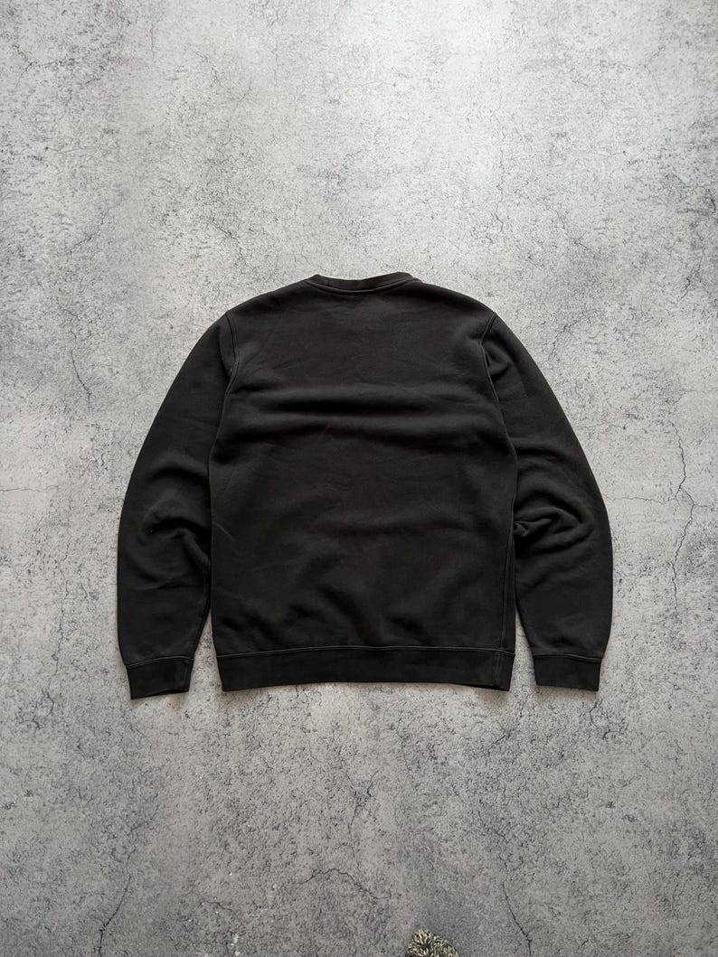 May include: A black crew neck sweatshirt. The sweatshirt is made of a soft material and has a ribbed neckline, cuffs, and hem. The back of the sweatshirt is visible in the image.