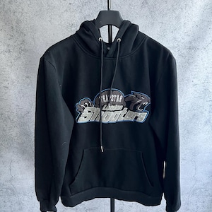May include: A black long-sleeve hooded sweatshirt featuring a central graphic with the text "Trapstar London Shooters" in white and silver lettering, accented by a blue outline and a stylized panther head icon on the right side of the design.