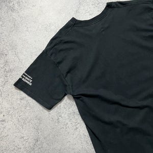 May include: Black t-shirt with the text "Everything is black and white, like Guinness" printed in white on the left sleeve. The shirt is made of a soft material.