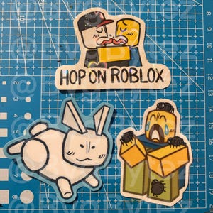 Könnte beinhalten: Eine Sammlung von Aufklebern mit Cartoon-Charakteren und dem Text "HOP ON ROBLOX". Ein Aufkleber zeigt zwei Figuren, die sich umarmen, ein weiterer ein weißes Kaninchen und der letzte eine Figur mit Spinnen.