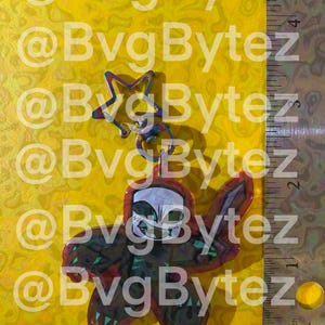 May include: A keychain with a star-shaped charm and a pendant featuring a skull design. The pendant is red and black with green accents. The background is yellow with the text "@BvgBytez".