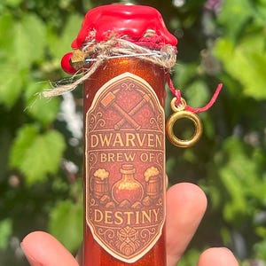 May include: A small, cylindrical bottle with a red wax seal and a decorative label. The label reads "Dwarven Brew of Destiny" with illustrations of a hammer, mugs of beer, and a central bottle. A gold-colored charm hangs from the bottle.