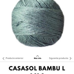 Puede incluir: Ovillo de hilo gris verdoso, probablemente para tejer o hacer ganchillo. El hilo está bien enrollado, mostrando la textura de las fibras. El nombre del producto "CASASOL BAMBU L" es visible.
