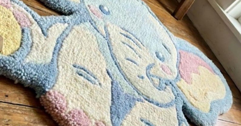 May include: A whimsical, tufted rug in the shape of a cartoon bunny. The rug features a light blue, cream, pink, and yellow color palette. The bunny's face and ears are clearly defined, creating a playful and inviting design.