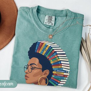 T-shirt with woman's profile and stack of books labeled with subjects.