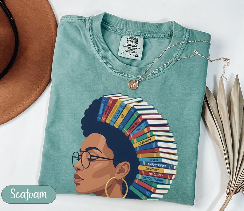 T-shirt with woman's profile and stack of books labeled with subjects.