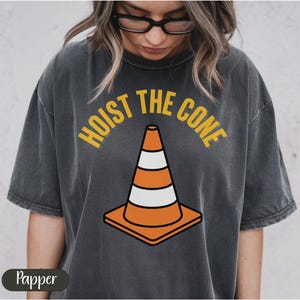 Black t-shirt with "Hoist the cone" text and traffic cone graphic.