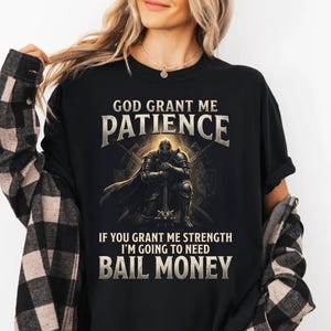 Puede incluir: Camiseta negra con el texto "GOD GRANT ME PATIENCE" sobre una ilustración de un caballero arrodillado con una maza. Debajo de la ilustración, el texto dice "IF YOU GRANT ME STRENGTH I'M GOING TO NEED BAIL MONEY."