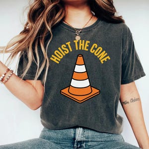 Orange traffic cone with white stripes, text "HOIST THE CONE".