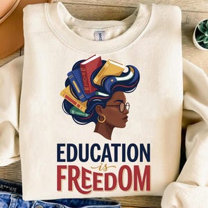 Cream sweatshirt with "Education is Freedom" graphic and woman with books in her hair.