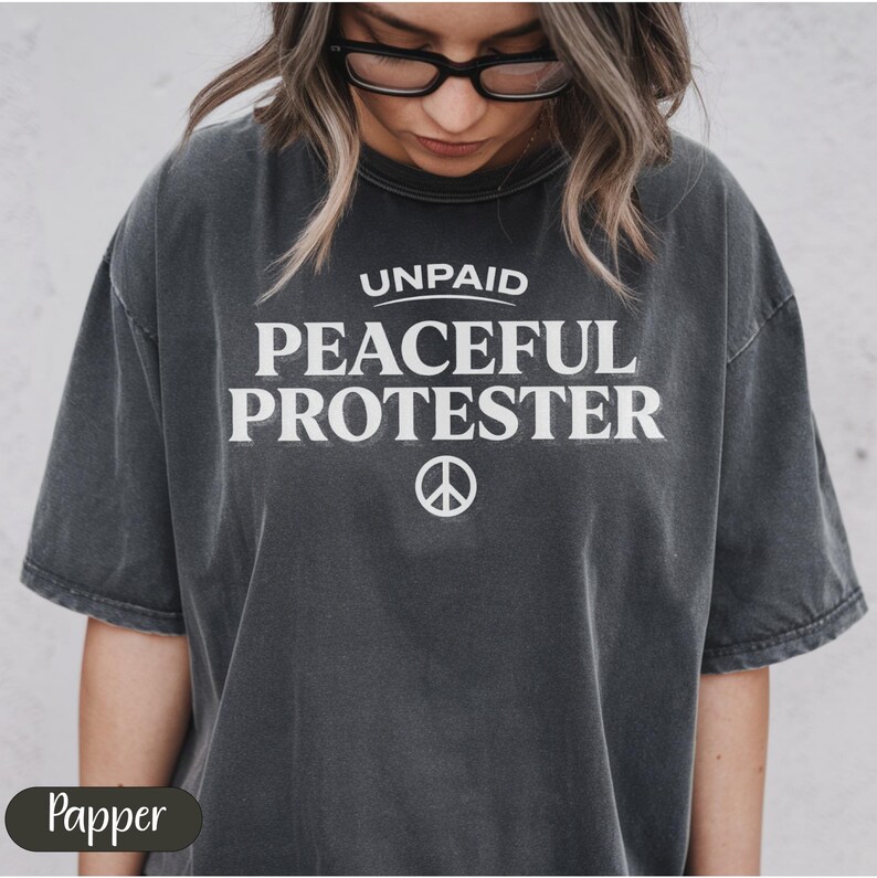 Dark gray t-shirt with "UNPAID PEACEFUL PROTESTER" and peace symbol.