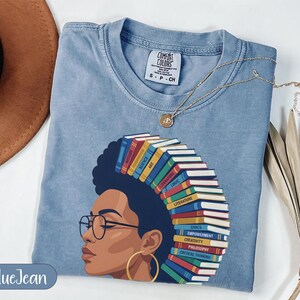 Blue t-shirt with woman's profile and spine of books representing subjects.