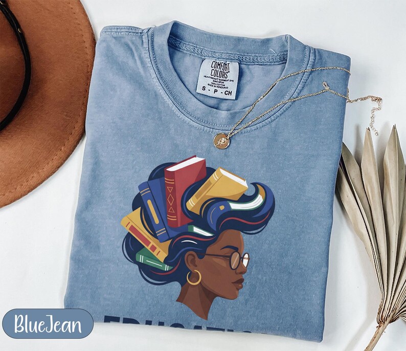 Blue t-shirt with woman's head adorned with books, gold necklace.
