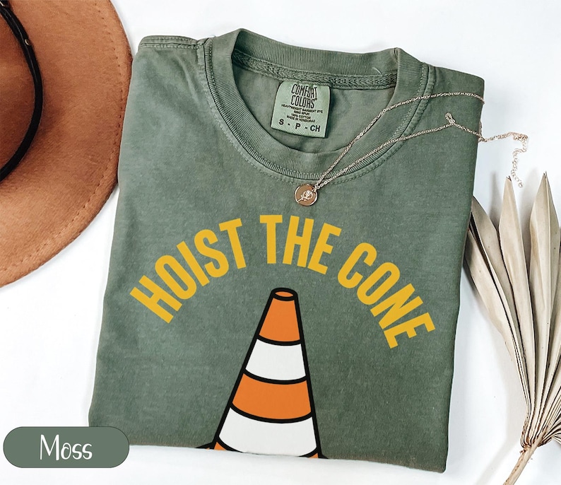 Green t-shirt with "HOIST THE CONE" text and traffic cone graphic.