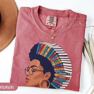 Red t-shirt with woman's profile, hair made of books with various subjects.