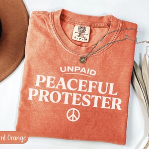 Comfort Colors burnt orange t-shirt with "UNPAID PEACEFUL PROTESTER" text.