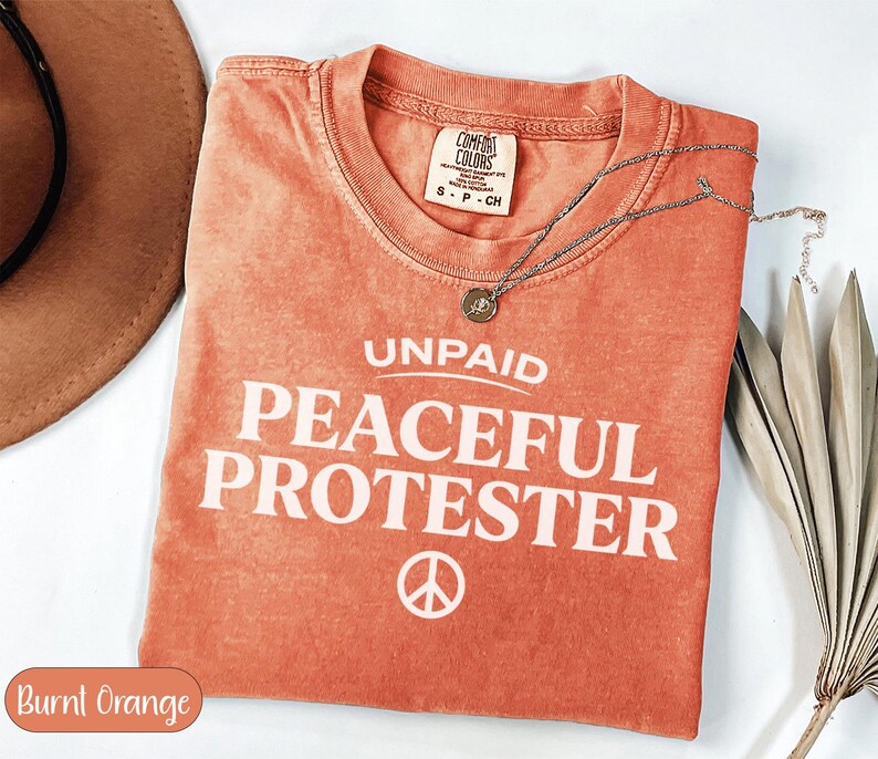 Comfort Colors burnt orange t-shirt with "UNPAID PEACEFUL PROTESTER" text.
