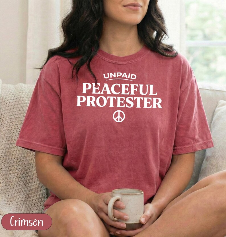 Crimson t-shirt with "Unpaid Peaceful Protester" and peace symbol.