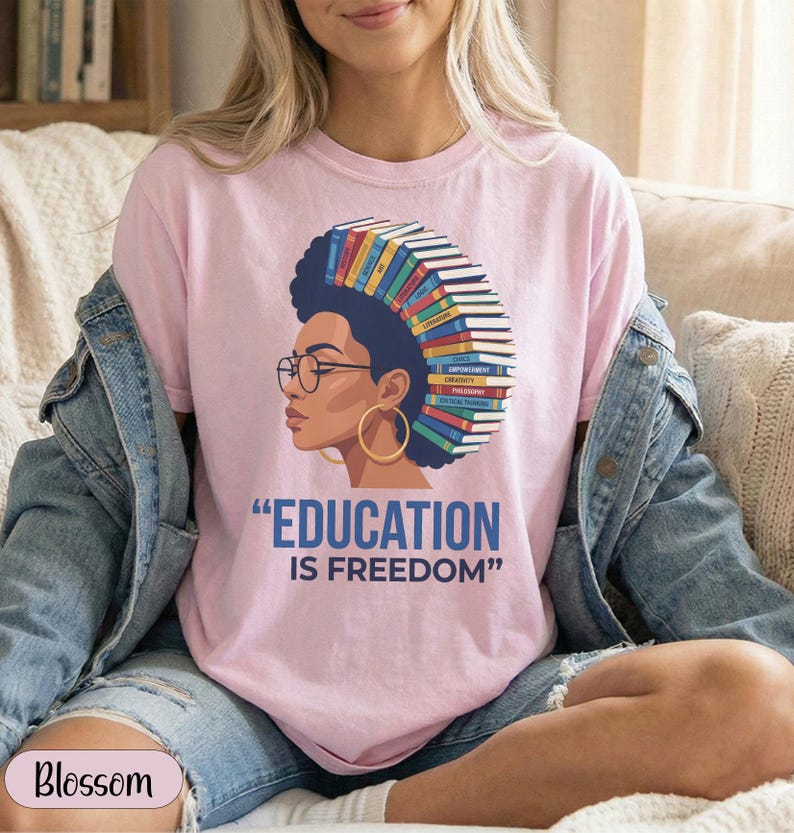 Pink t-shirt with graphic of woman with books on head, "EDUCATION IS FREEDOM" text.