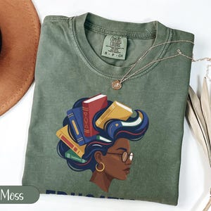 Green t-shirt with woman's profile and books in her hair.