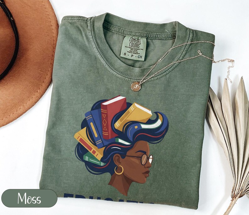 Green t-shirt with woman's profile and books in her hair.