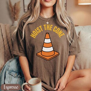 Brown t-shirt with "Hoist the Cone" text and a traffic cone graphic.