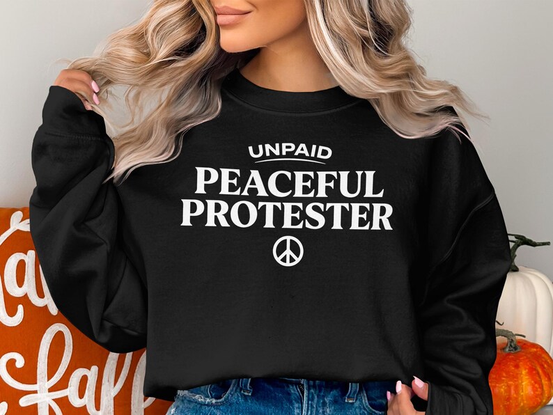 Black sweatshirt with "Unpaid Peaceful Protester" and a peace symbol.