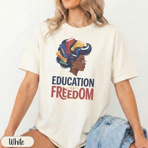 Woman with books in her hair wearing "EDUCATION IS FREEDOM" t-shirt.