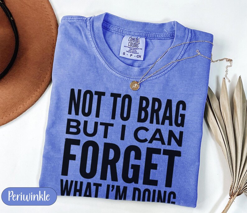 Periwinkle Comfort Colors t-shirt with "NOT TO BRAG BUT I CAN FORGET WHAT I'M DOING" text.