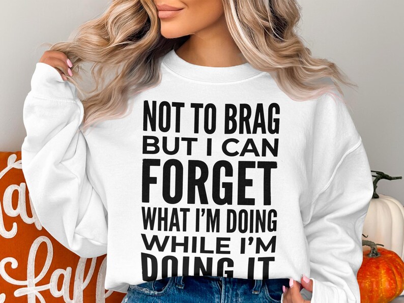 White sweatshirt with black text that reads "NOT TO BRAG BUT I CAN FORGET WHAT I'M DOING WHILE I'M DOING IT."