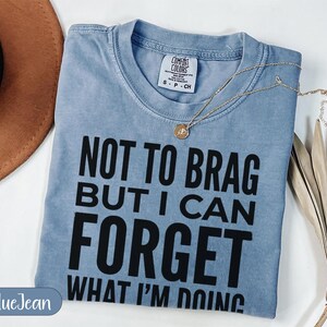 Blue t-shirt with "NOT TO BRAG BUT I CAN FORGET WHAT I'M DOING" text.