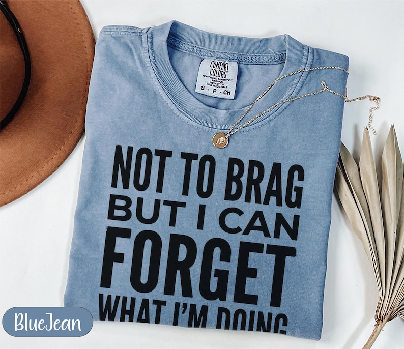 Blue t-shirt with "NOT TO BRAG BUT I CAN FORGET WHAT I'M DOING" text.