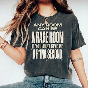 May include: Dark gray t-shirt with the text "ANY ROOM CAN BE A RAGE ROOM IF YOU JUST GIVE ME AF*ING SECOND" in white. The shirt is a casual style, suitable for everyday wear.