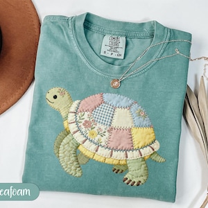 May include: A set of three ceramic mugs with a speckled, matte finish. The mugs are in shades of cream, light grey, and dark grey. Each mug has a simple, minimalist design, ideal for coffee or tea.