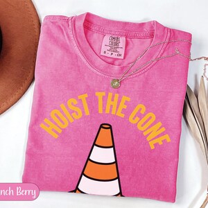 Pink t-shirt with "HOIST THE CONE" text and a traffic cone graphic.