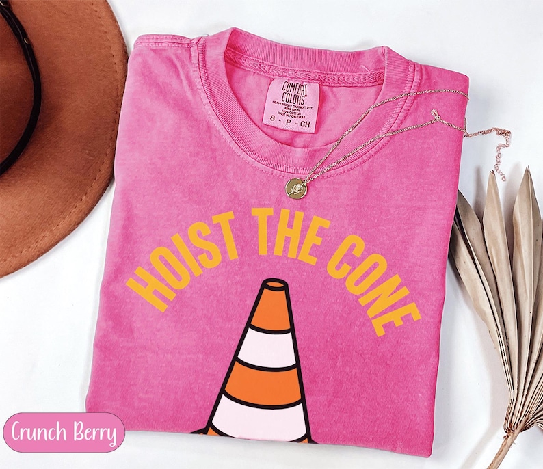 Pink t-shirt with "HOIST THE CONE" text and a traffic cone graphic.