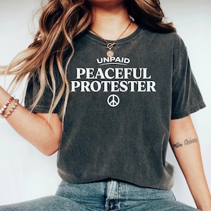Dark t-shirt with "Unpaid Peaceful Protester" and peace symbol.