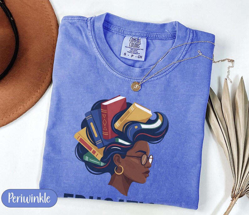Periwinkle t-shirt with graphic of a woman's head with books for hair.