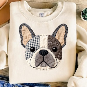 Cream sweatshirt featuring a patchwork French bulldog face with plaid and textured fabric.
