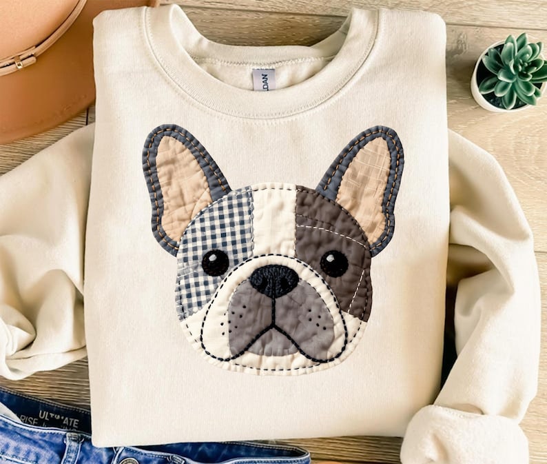 Cream sweatshirt featuring a patchwork French bulldog face with plaid and textured fabric.