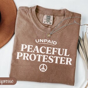 Comfort Colors Espresso t-shirt with "Unpaid Peaceful Protester" and peace symbol.