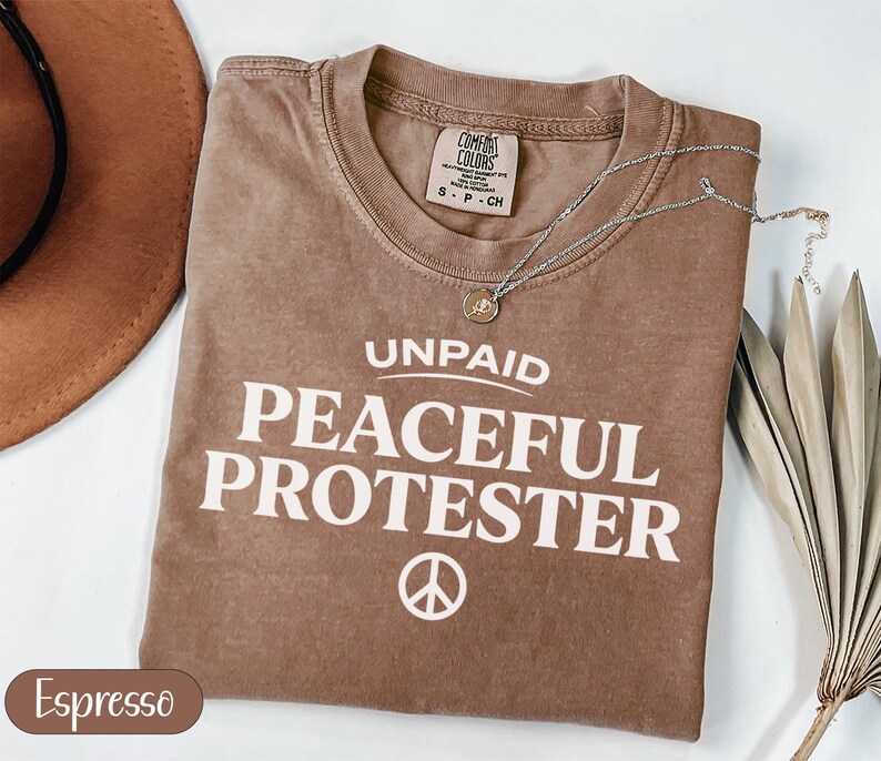 Comfort Colors Espresso t-shirt with "Unpaid Peaceful Protester" and peace symbol.