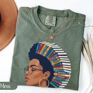 Green t-shirt with a graphic of a woman's profile adorned with books.