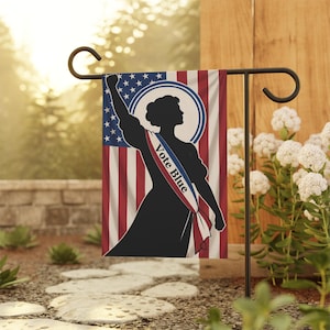 Könnte beinhalten: Eine rechteckige Gartenflagge mit der schwarzen Silhouette einer Person, die einen Arm zur Faust erhoben hat. Der Hintergrund zeigt die amerikanische Flagge mit roten, weißen und blauen Streifen und Sternen. Eine weiße Schärpe trägt die Aufschrift Vote Blue.