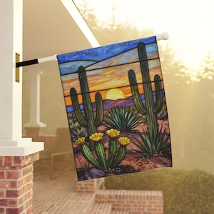 May include: A rectangular garden flag featuring a stained glass style desert landscape with tall saguaro cacti, blooming yellow flowers, and agave plants under a sunset sky with orange, yellow, and blue hues, mounted on a white metal pole.
