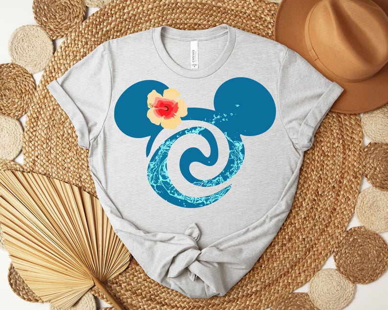 Puede incluir: Camiseta gris claro con una silueta azul de Mickey Mouse, un dise&ntilde;o de remolino de agua y una flor amarilla y roja. La camiseta est&aacute; hecha de un material suave y tiene cuello redondo.