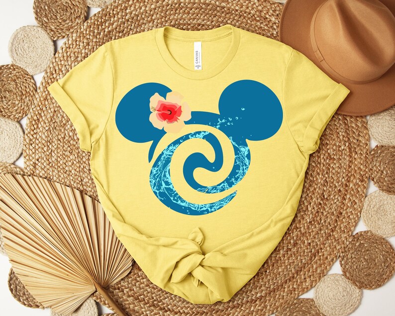 Puede incluir: Camiseta amarilla con una silueta azul de Mickey Mouse, un acento floral y un dise&ntilde;o acu&aacute;tico. La camiseta est&aacute; hecha de un material suave, ideal para el uso diario.